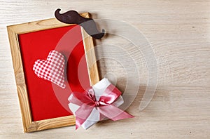 Father`s Day Background Heart in a frame on a red background, with a gift box and black mustache. Free space for text. Happy fath