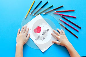 Father`s day. a boy draws a postcard to his father with pencils. Children`s love