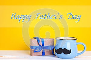 Father`s Day card with blue mug with a mustache and gift box on