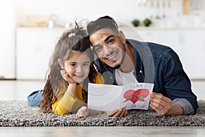 Father's Day Celebration. Happy Arab Man With Handmade Greeting Card And Daughter
