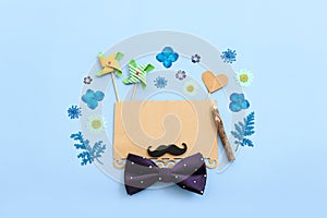 Father's day concept. bow tie, flowers, funny moustache and empty note over blue background. top view, flat lay