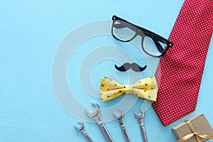 Father`s day concept. gift box, tie and funny moustache over wooden background. top view, flat lay