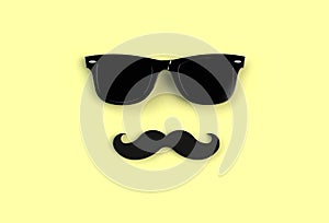 Father`s day concept. Hipster black sunglasses and funny moustache on yellow background