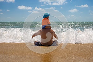 Father`s day. dad with a baby on his shoulders playing in the spray of sea foam. happy childhood concept