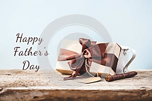 Father`s Day. Gift box with a tag and coffee cup on a wooden background Copy space Text