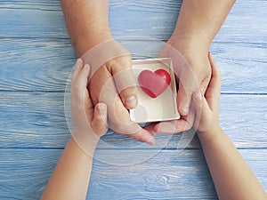 Father`s Day Hands Dad and Child Gift Box Heart on a Blue Wooden Background