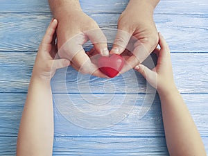 Father`s Day Hands Dad and Child holding Heart on a Blue Wooden Background