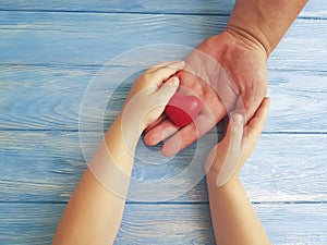 Father`s Day Hands Dad and Child holding thankful Heart on a Blue Wooden Background