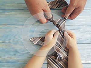 father`s day hands dad and child tie against blue wooden background