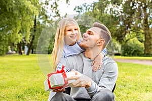 Father`s day. Happy family daughter hugging dad and laughs on holiday. Girl gave dad a gift in the park