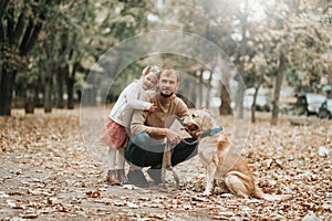 Father`s day. Happy family daughter hugging dad and laughs outdoor in park. Father and daughter with their lovely dog playing in