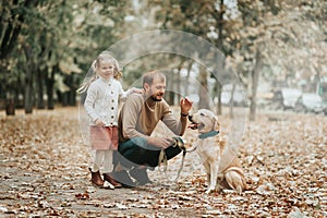 Father`s day. Happy family daughter hugging dad and laughs outdoor in park. Father and daughter with their lovely dog playing in