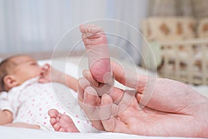 A father`s hand touches the leg of his adorable newborn daughter.