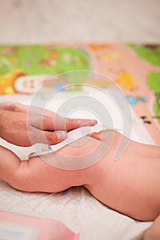 Father`s hand wipes baby`s buttocks with wet wipe in selective focus. daily children`s hygiene. paternity concept