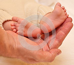 Father's hands cradling his infant son's feet photo