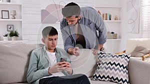 Father scolding his son while he using smartphone at home. Teenager problems
