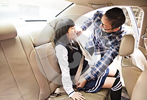 Father securing daughter in the car seat