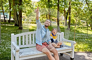 Father showing something to son sitting on bench