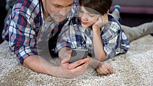 Father showing son funny application on smartphone, spending time together