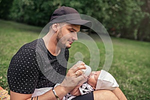 Father sitting outside feeding his baby boy with a bottle