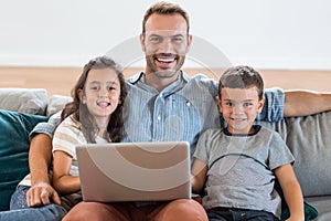 Father sitting on sofa with son and daughter