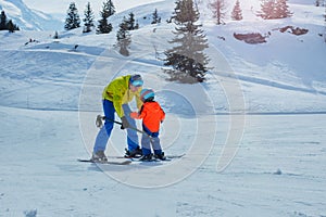 Father in skiing school glide backwards teach child to ski