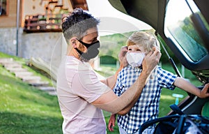 Father with small son going on trip by car, wearing face masks.