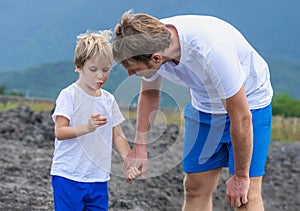 Syn alebo dospelý mladší brat chôdze spoločne. chlapec nájdených ukázať neobvyklý kameň v ruke prsty muž pozorný 