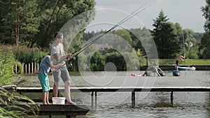 Father and son angling with spinning rod at lake