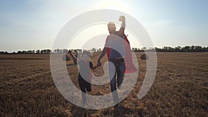 Father and son as superheroes running across field