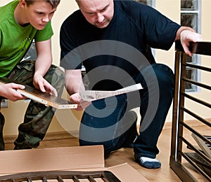 Father and son assemble cot