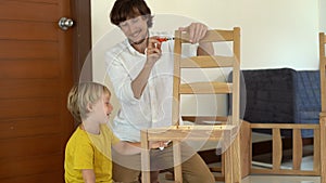 Father and son assemble wooden furniture from small parts. Little boy helps his father to assemble a chair.