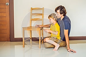 Father and son assembling furniture. Boy helping his dad at home. Happy Family concept