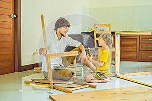 Father and son assembling furniture. Boy helping his dad at home. Happy Family concept