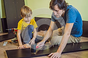 Father and son assembling furniture. Boy helping his dad at home. Happy Family concept