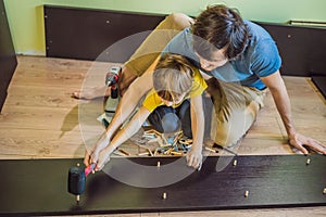 Father and son assembling furniture. Boy helping his dad at home. Happy Family concept