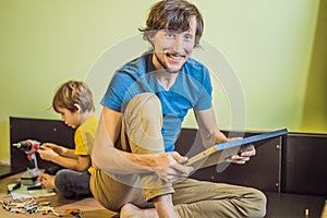 Father and son assembling furniture. Boy helping his dad at home. Happy Family concept