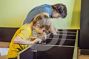 Father and son assembling furniture. Boy helping his dad at home. Happy Family concept