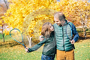 Father and son in the autumn park with tennis rackets