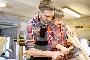 Father and son with ax and wood plank at workshop