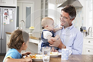 Father, Son And Baby Daughter Having Meal In Kitchen Together