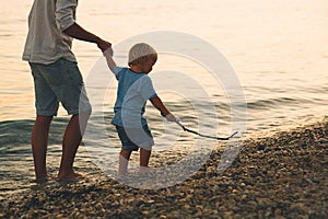 Father and son back silhouettes walking by the sea.