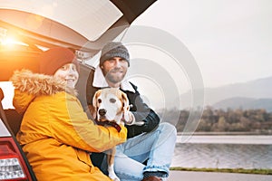 Father and son with beagle dog siting together in car trunk and photo