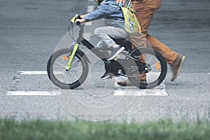 Father and son on a bicycle crossing the walkway to the school. Single parent concept and empty copy space