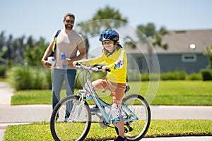 Father and son in bike helmet for learning to ride bicycle at park. Father helping son cycling. Father and son on the