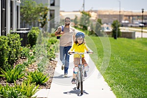 Father and son in bike helmet for learning to ride bicycle at park. Father helping son cycling. Father and son on the