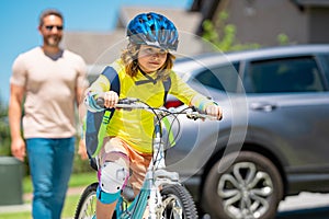 Father and son in bike helmet for learning to ride bicycle at park. Father helping son cycling. Father and son on the