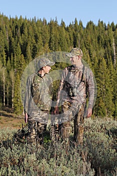 Father and son bow hunting together in woods