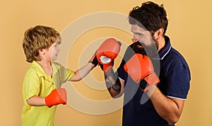 Father and son during boxing training. Child boy boxer in gloves practicing punches with coach.
