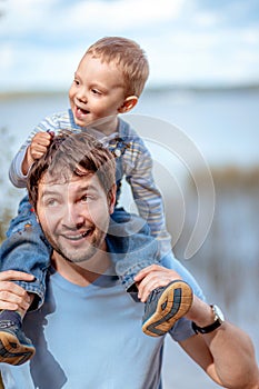 father and son. Boy sitting on man shoulders